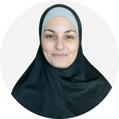 An arab woman wearing embroidered black hijab and smiling at the camera